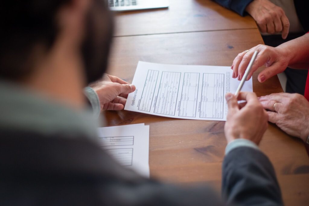 Parents meeting with an insurance agent to review liability limits and accident forgiveness options before their teenager begins driving to school.